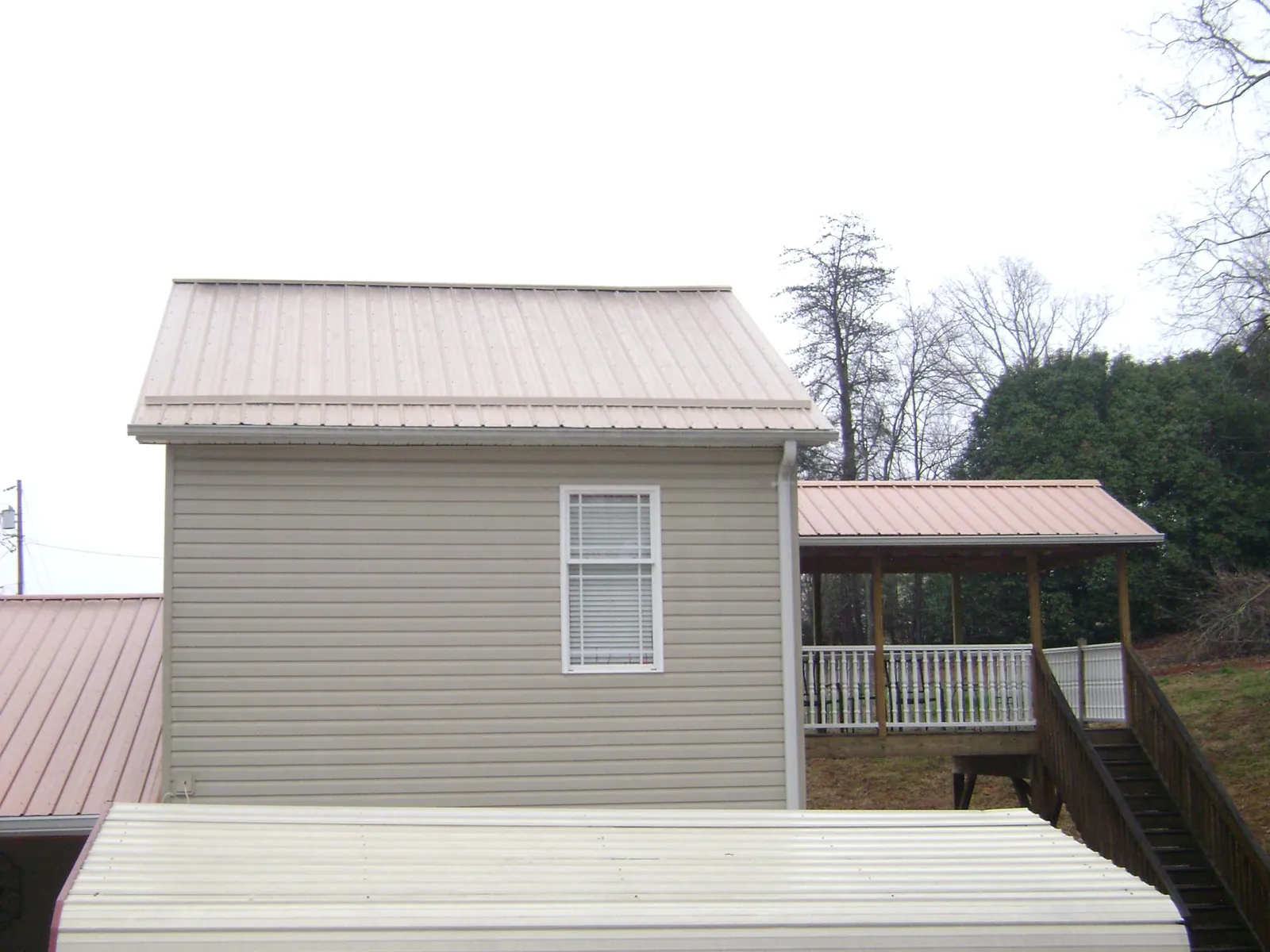 Tan metal roofs on a two story addition and attached porch, from a Roof Replacement job in Mechanicsburg